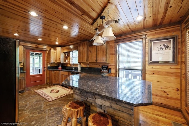 kitchen with kitchen peninsula, stainless steel fridge, plenty of natural light, and hardwood / wood-style flooring