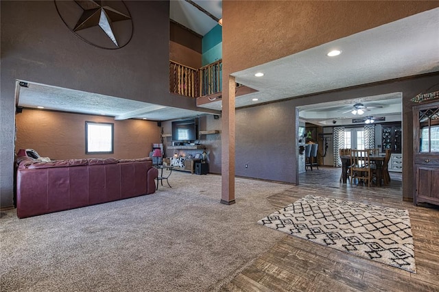 living room with carpet flooring, ceiling fan, and a textured ceiling