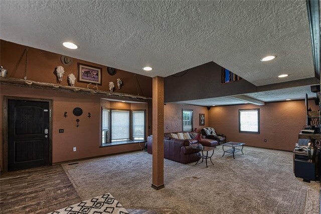 living room featuring beamed ceiling, hardwood / wood-style floors, and a textured ceiling