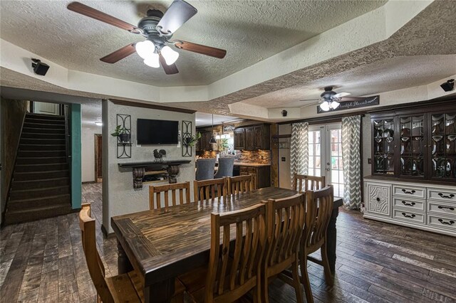 dining area with ceiling fan, french doors, dark hardwood / wood-style floors, and a textured ceiling