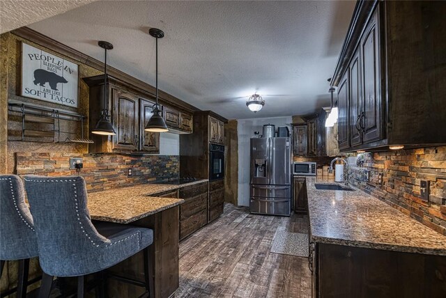 kitchen with pendant lighting, sink, black appliances, and dark hardwood / wood-style floors