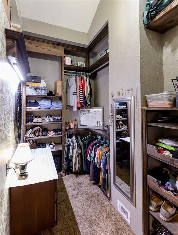 walk in closet with carpet floors and lofted ceiling