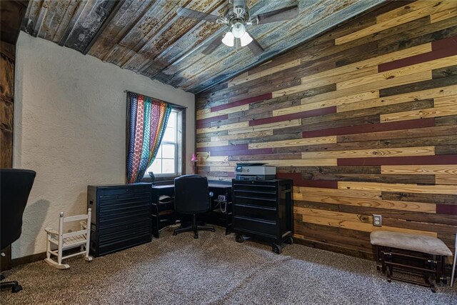 carpeted home office featuring ceiling fan, lofted ceiling, and wood walls