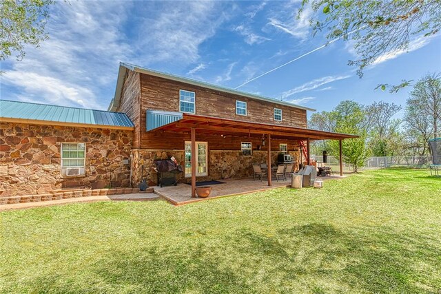 rear view of property featuring a lawn, a patio area, and a trampoline