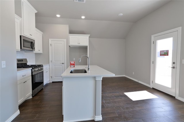 kitchen with white cabinetry, sink, vaulted ceiling, a center island with sink, and appliances with stainless steel finishes