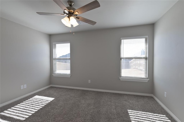 spare room featuring ceiling fan and dark carpet