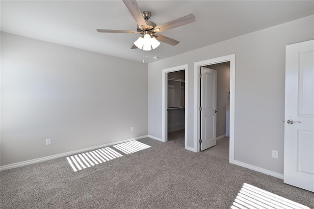 unfurnished bedroom featuring carpet, a walk in closet, a closet, and ceiling fan