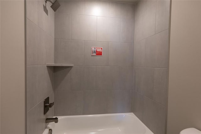 bathroom featuring tiled shower / bath combo and toilet