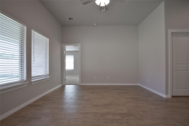 unfurnished room featuring dark hardwood / wood-style flooring, a wealth of natural light, and ceiling fan