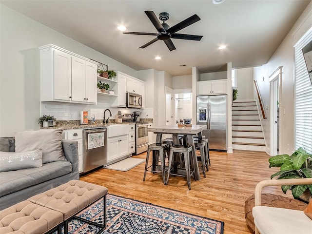 kitchen featuring ceiling fan, white cabinetry, stainless steel appliances, and light hardwood / wood-style flooring