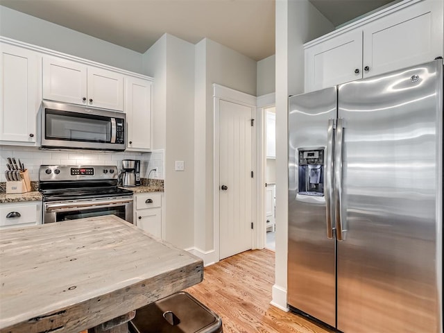 kitchen with white cabinets, stainless steel appliances, and light stone counters