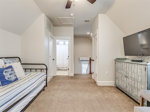 bedroom featuring lofted ceiling, light carpet, and ensuite bath