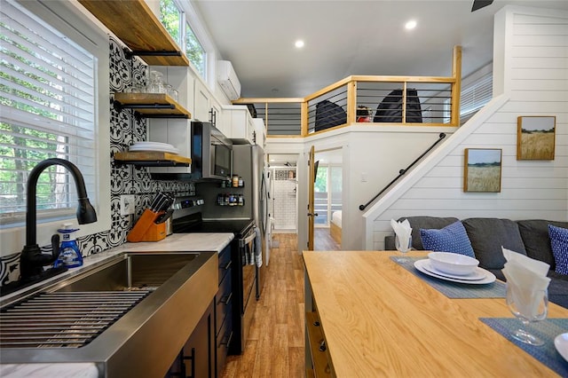 kitchen featuring a wall mounted air conditioner, sink, electric stove, light hardwood / wood-style flooring, and white cabinets