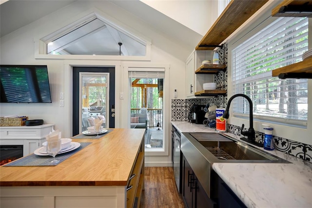 kitchen with butcher block counters, a center island, dark wood-type flooring, and lofted ceiling