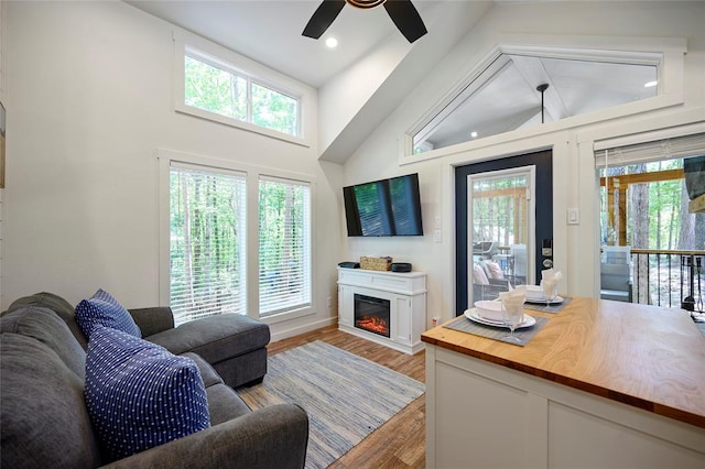 living room with ceiling fan, light wood-type flooring, and high vaulted ceiling