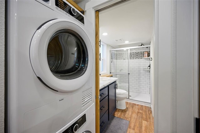 clothes washing area with light wood-type flooring and stacked washer and clothes dryer