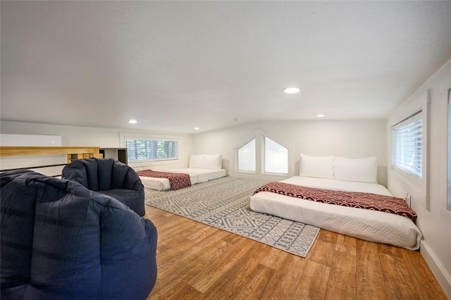 bedroom with multiple windows, vaulted ceiling, and hardwood / wood-style flooring