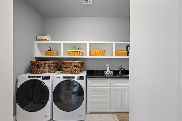 clothes washing area with cabinets, washer and clothes dryer, and sink