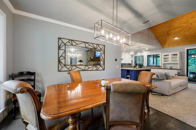 dining space with hardwood / wood-style floors, crown molding, and vaulted ceiling