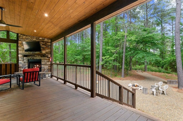 wooden deck with ceiling fan and an outdoor stone fireplace