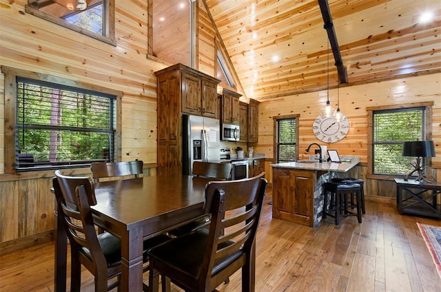 dining area with a wealth of natural light, wood-type flooring, and wood walls