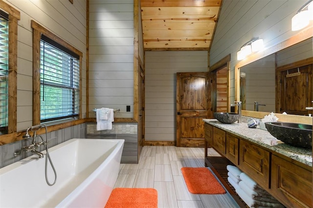 bathroom featuring vanity, a bathtub, wooden ceiling, wooden walls, and vaulted ceiling