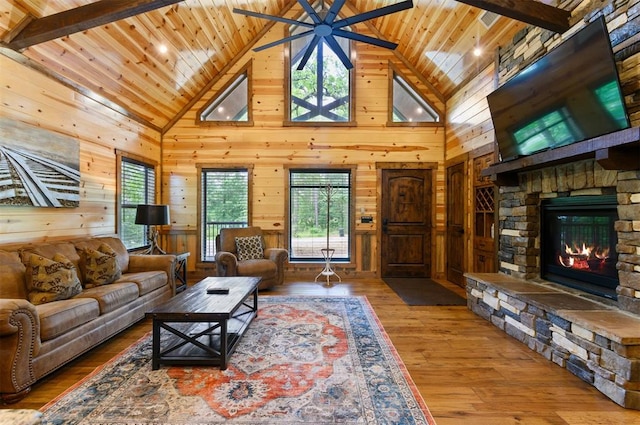 living room with hardwood / wood-style floors, high vaulted ceiling, a wealth of natural light, and wood walls