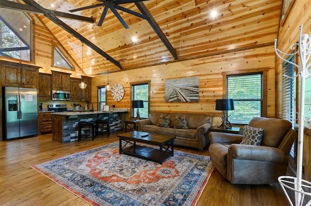 living room with wooden walls, high vaulted ceiling, a healthy amount of sunlight, and wood-type flooring