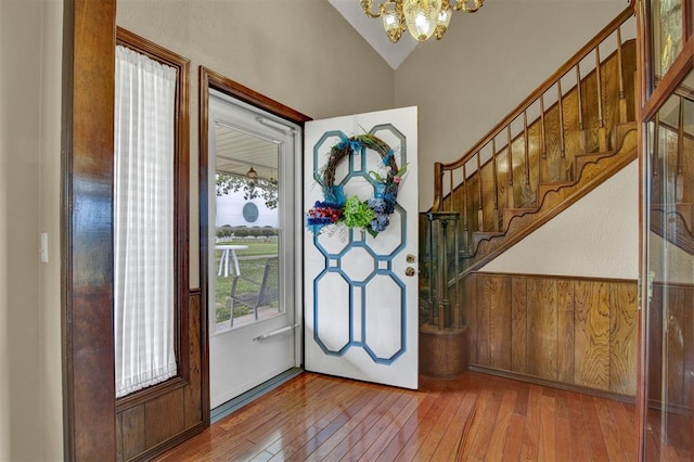 foyer entrance with hardwood / wood-style flooring, vaulted ceiling, and a notable chandelier