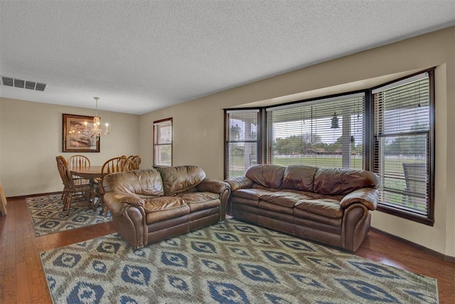 living room featuring a textured ceiling, dark hardwood / wood-style floors, and an inviting chandelier