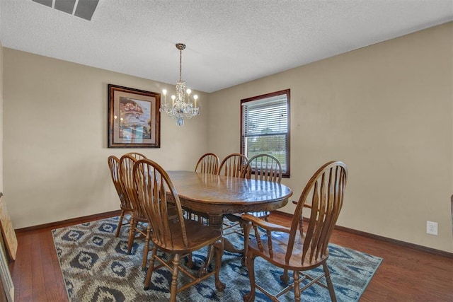 dining space with a textured ceiling, dark hardwood / wood-style floors, and a notable chandelier