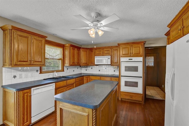 kitchen featuring sink, a kitchen island, dark hardwood / wood-style floors, and white appliances