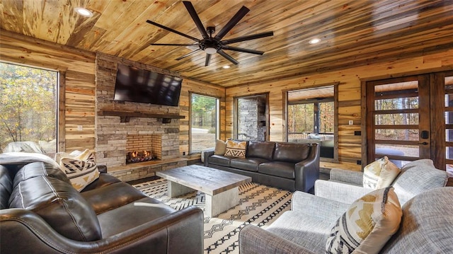 living room with wood walls, plenty of natural light, ceiling fan, and wooden ceiling