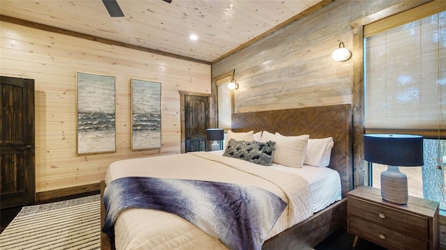 bedroom featuring multiple windows, wood-type flooring, ceiling fan, and wood walls