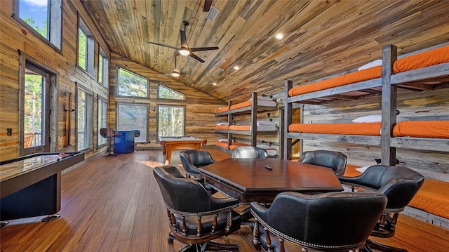 office area with a wealth of natural light, hardwood / wood-style floors, high vaulted ceiling, and wooden walls