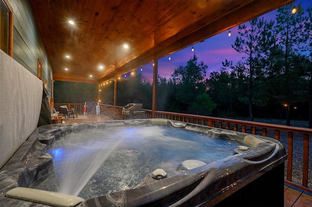 pool at dusk with a hot tub