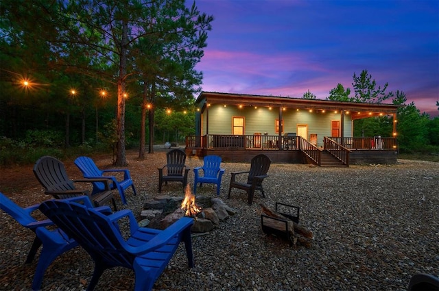 back house at dusk with a wooden deck and an outdoor fire pit