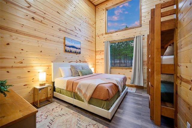 bedroom with a towering ceiling, dark hardwood / wood-style flooring, and wood walls