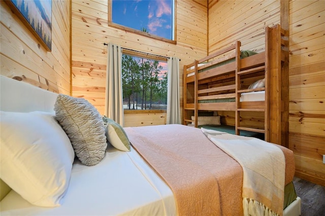 bedroom featuring wood walls, hardwood / wood-style floors, and a towering ceiling