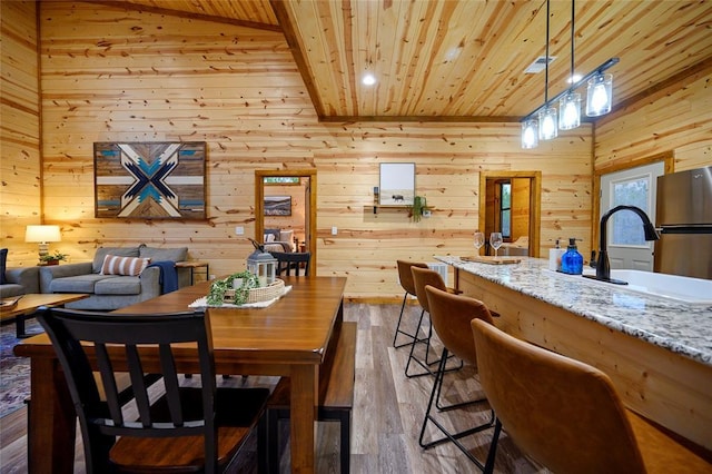 dining room featuring dark hardwood / wood-style flooring, wooden walls, wooden ceiling, and sink