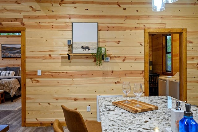 interior space with hardwood / wood-style flooring, washer and clothes dryer, and wooden walls