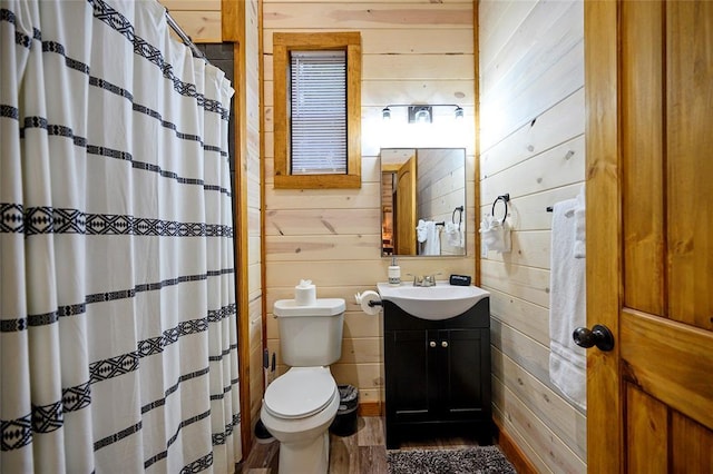 bathroom with vanity, toilet, and wooden walls