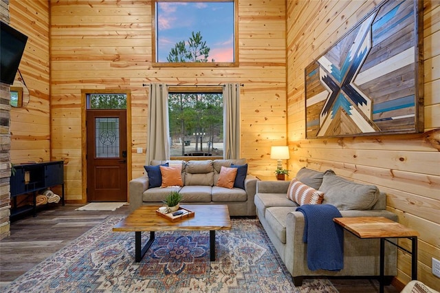 living room featuring dark hardwood / wood-style floors, a high ceiling, and wooden walls