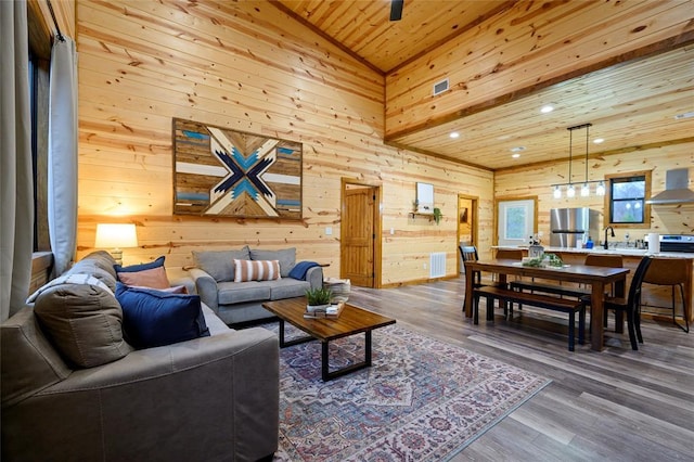 living room featuring wood-type flooring, sink, wooden walls, and wood ceiling