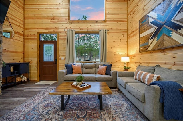 living room featuring a skylight, wood walls, a towering ceiling, and wood-type flooring