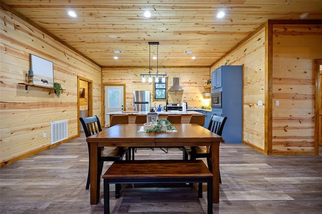 dining area with light hardwood / wood-style floors, wood walls, and wood ceiling