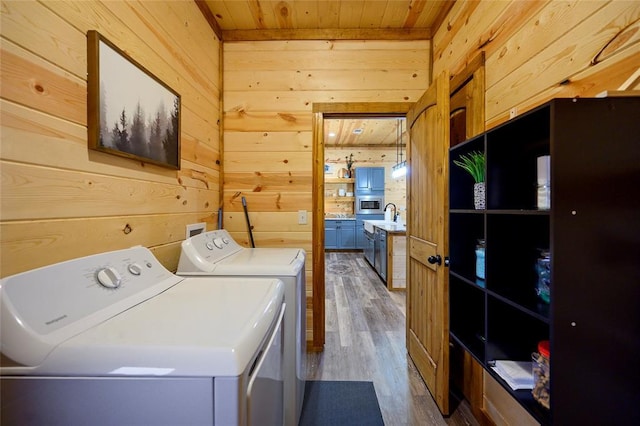 laundry area featuring hardwood / wood-style floors, separate washer and dryer, and wood walls