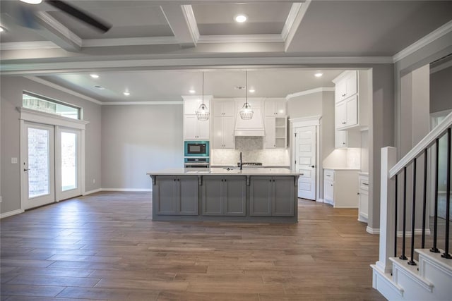 kitchen with white cabinets, decorative light fixtures, dark hardwood / wood-style flooring, and a kitchen island with sink