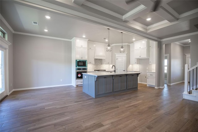 kitchen with white cabinetry, black microwave, stainless steel oven, and a spacious island