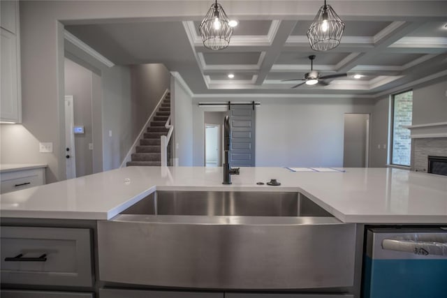 kitchen featuring a barn door, a stone fireplace, a kitchen island, and coffered ceiling